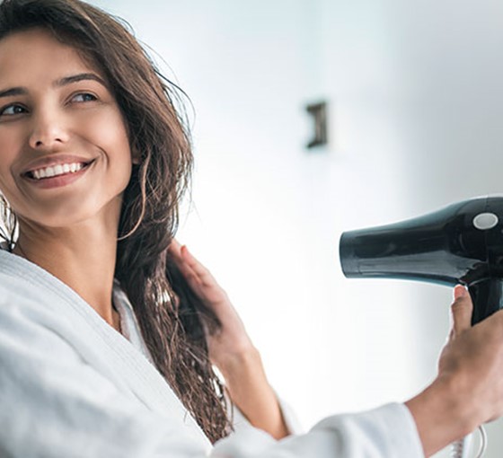 Frau föhnt nasse Haare Mit nassen Haaren ins Freie